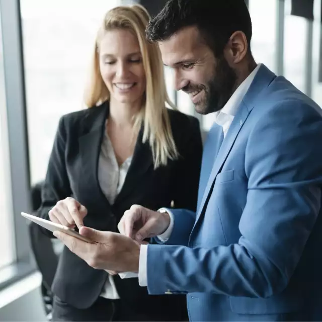 Two people in suits looking at tablet