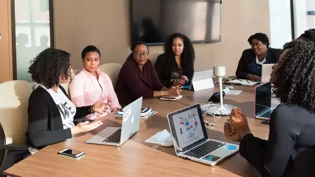 8 people sit around a conference table in discussion