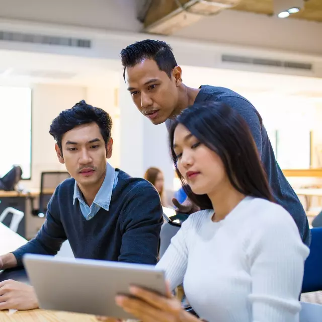 Three employees looking at tablet