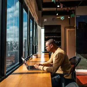 Professional using a laptop in a modern office with city views—representing business users evaluating SteelBrick Salesforce CPQ alternatives.