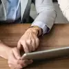 Close-up of two colleagues collaborating on a project using a digital tablet at a desk.
